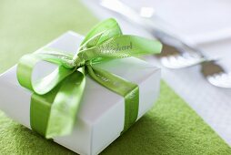 Small gift with green ribbon beside forks