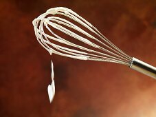 A whisk with whipped cream