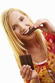 A young woman bitting a piece of dark chocolate