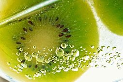 Slice of kiwi fruit and air bubbles in a glass