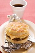 Cheeseburger with scrambled egg on aluminium foil, coffee cup