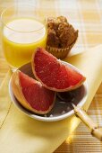 Grapefruit in a bowl, muffin and juice behind