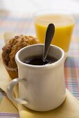 Ein Becher Kaffee, Muffin und Orangensaft