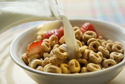 Cerealien in einer Schale werden mit Milch begossen
