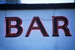 Neonbuchstaben (Bar) an einem Gebäude