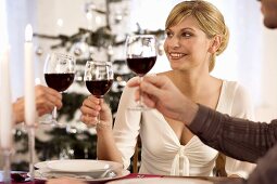 Young woman clinking wine glasses with two people