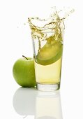 Apfelspalt fällt in ein Glas Apfelsaft