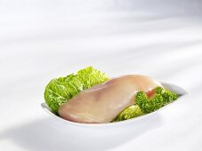 Raw chicken breast fillet on lettuce leaf