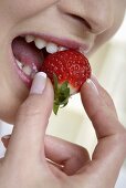 Woman biting into a strawberry