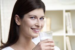 Frau mit Milchbart hält ein Glas Milch in der Hand