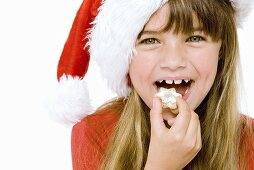 Girl in Father Christmas hat eating a cinnamon star