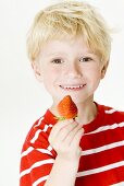 Smiling boy with a strawberry in his hand