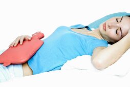Young woman with a hot-water bottle on her stomach