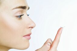 Frau mit Kontaktlinse auf dem Finger