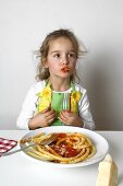 Girl eating macaroni with tomato sauce