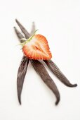 Half a strawberry on three vanilla pods