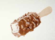 Chocolate-coated vanilla ice cream with nuts on stick