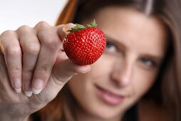 Junge Frau hält eine Erdbeere in der Hand