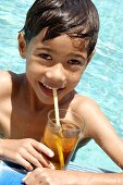Kleiner Junge mit Eistee im Pool
