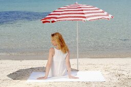 Woman sitting under a beach umbrella on the beach
