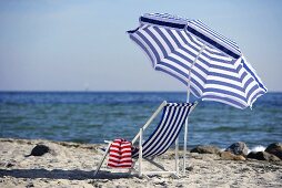 Blue and white deckchair and beach umbrella by the sea