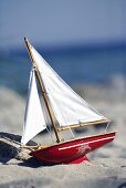 Toy sailing boat on sandy beach