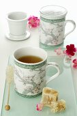 Tea in two Asian mugs, rock sugar, flowers