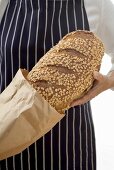 Woman putting a loaf of oat bread into a paper bag