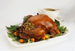 Stuffed turkey on a platter with gravy boat