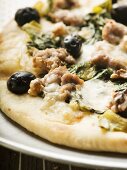 Pizza mit Hackfleisch, Oliven, Spinat und Käse (Close Up)