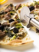Pizza mit Hackfleisch, Oliven, Spinat und Käse (halbiert)