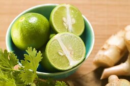 Limes in bowl, coriander leaves and galanga