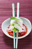 Vietnamese spring roll on chopsticks over chili sauce