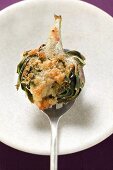 Stuffed artichoke with gratin topping on spoon