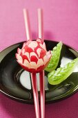 Radish flower on chopsticks, carved cucumber leaves