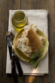 Pieces of white bread on plate with olive sprig, olive oil