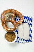 Two Weisswurst in packaging, pretzel & mustard