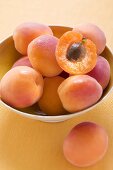 Whole apricots and half an apricot in yellow bowl