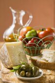 Tomaten im Drahtkorb, Oliven, Käse, Brot und Olivenöl