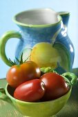Tomatoes in green bowl in front of ceramic jug