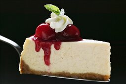 Slice of cheesecake with cherries, cream, mint on cake server