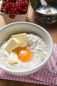 Flour, butter, egg in bowl, redcurrants and baking tin