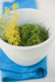 Chopped dill with flower in bowl on blue cloth