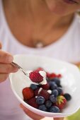 Woman eating berry muesli with yoghurt