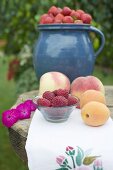 Apricots, peaches and berries on table out of doors