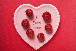 Strawberries on pink heart-shaped plate (overhead view)