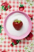 Strawberry in a small dish of sugar