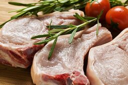 Raw pork chops with rosemary and tomatoes