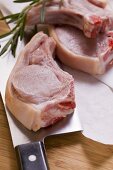 Raw pork chops with meat cleaver and rosemary