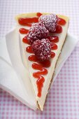 Piece of cheesecake with raspberries & icing sugar on napkin